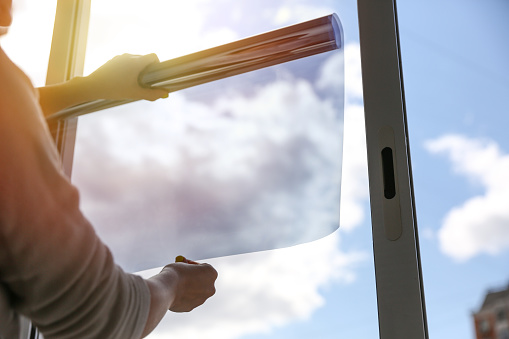 A professional applying a tint film on the window of a residential home in Palm Coast, FL
