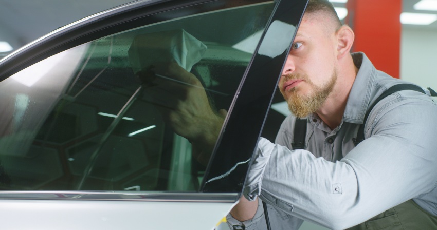 A technician installing tint film on a car window by Pro Tint LLC in Palm Coast, FL