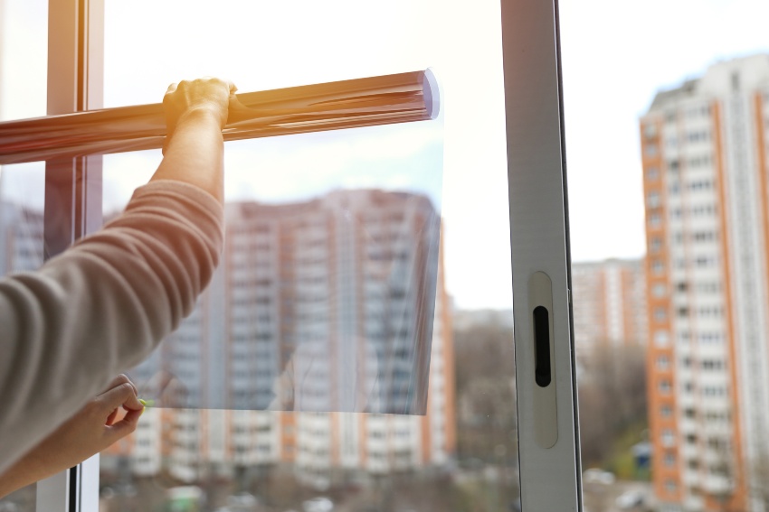 Applying window film to block heat and cut cooling costs in summer by Pro Tint LLC
